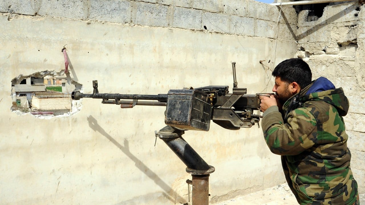 Ein syrischer Soldat hält hinter einer Mauer in einem Vorort von Damaskus Wache.