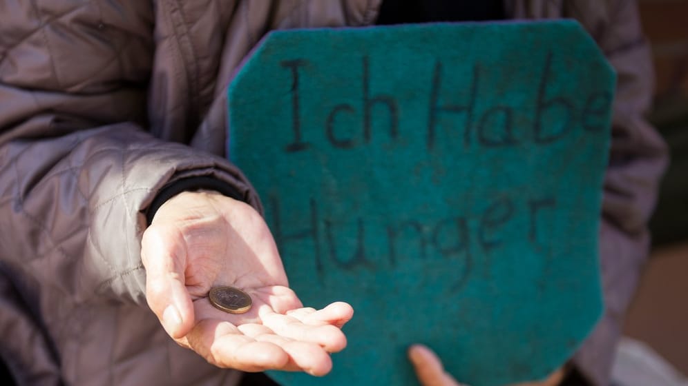 Eine Frau bittet in Hamburg mit einem Schild mit der Aufschrift "Ich habe Hunger" um Spenden.