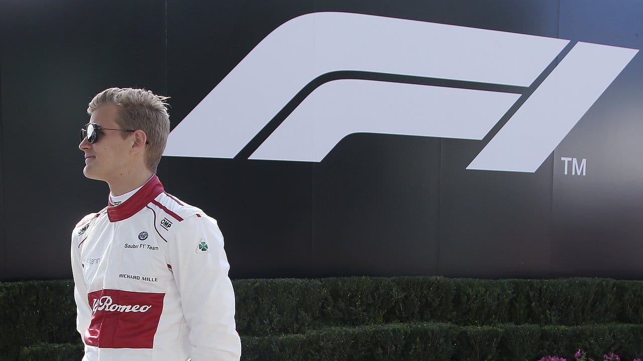 Ein Rennfahrer geht an dem neuen Logo der Formel 1 vorbei.