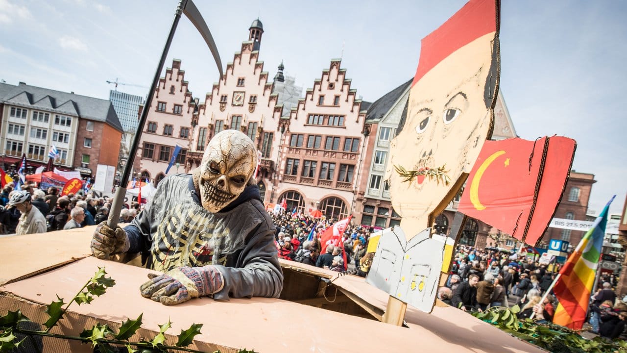 Ein als Tod verkleideter Demonstrant steht auf dem Frankfurter Römerberg auf einem Leopard-Panzer aus Pappe neben einem Bildnis des türkischen Präsidenten Erdogan.
