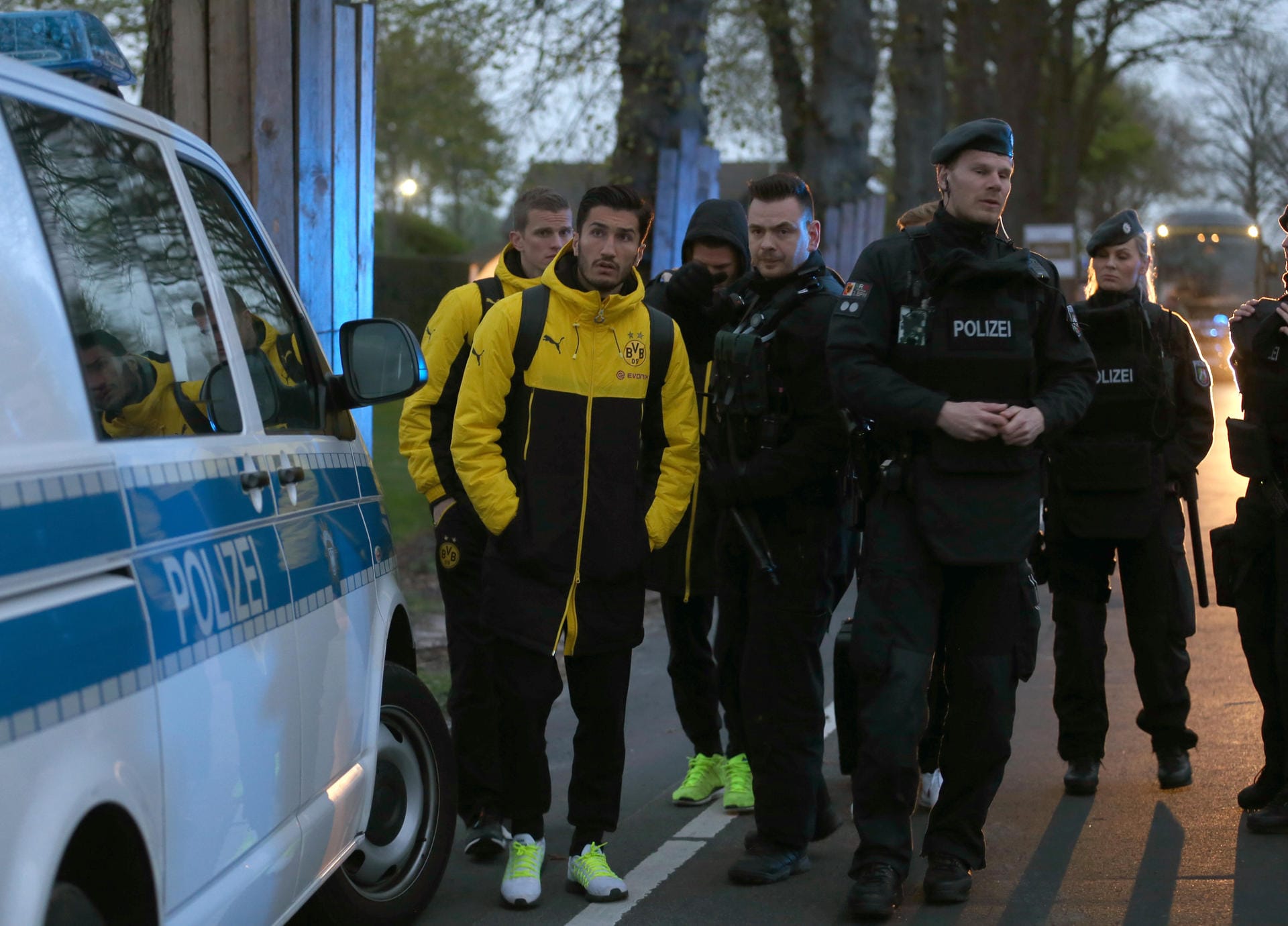 Die BVB-Stars Sven Bender und Nuri Sahin (v.l.) haben sich in Sicherheit gebracht und werden von Polizisten beschützt.