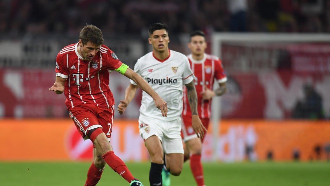 Bayern-Kapitän Thomas Müller (l) zieht ab, Sevillas Carlos Joaquin Correa hat das Nachsehen.
