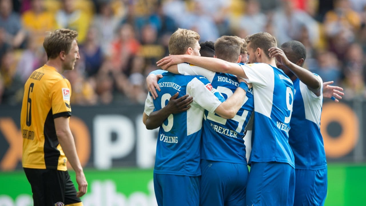 Die Spieler von Holstein Kiel feiern neben einem frustrierten Dresdner das Tor zur 1:0-Führung.