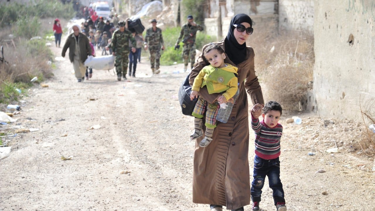 Eine Mutter verlässt mit ihren Kindern das umkämpfte Rebellengebiet.