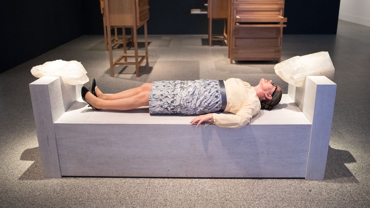 Eine Frau liegt in der Ausstellung "Marina Abramovic - The Cleaner" in der Bundeskunsthalle auf dem Werk "Bed for Human Use (III)".