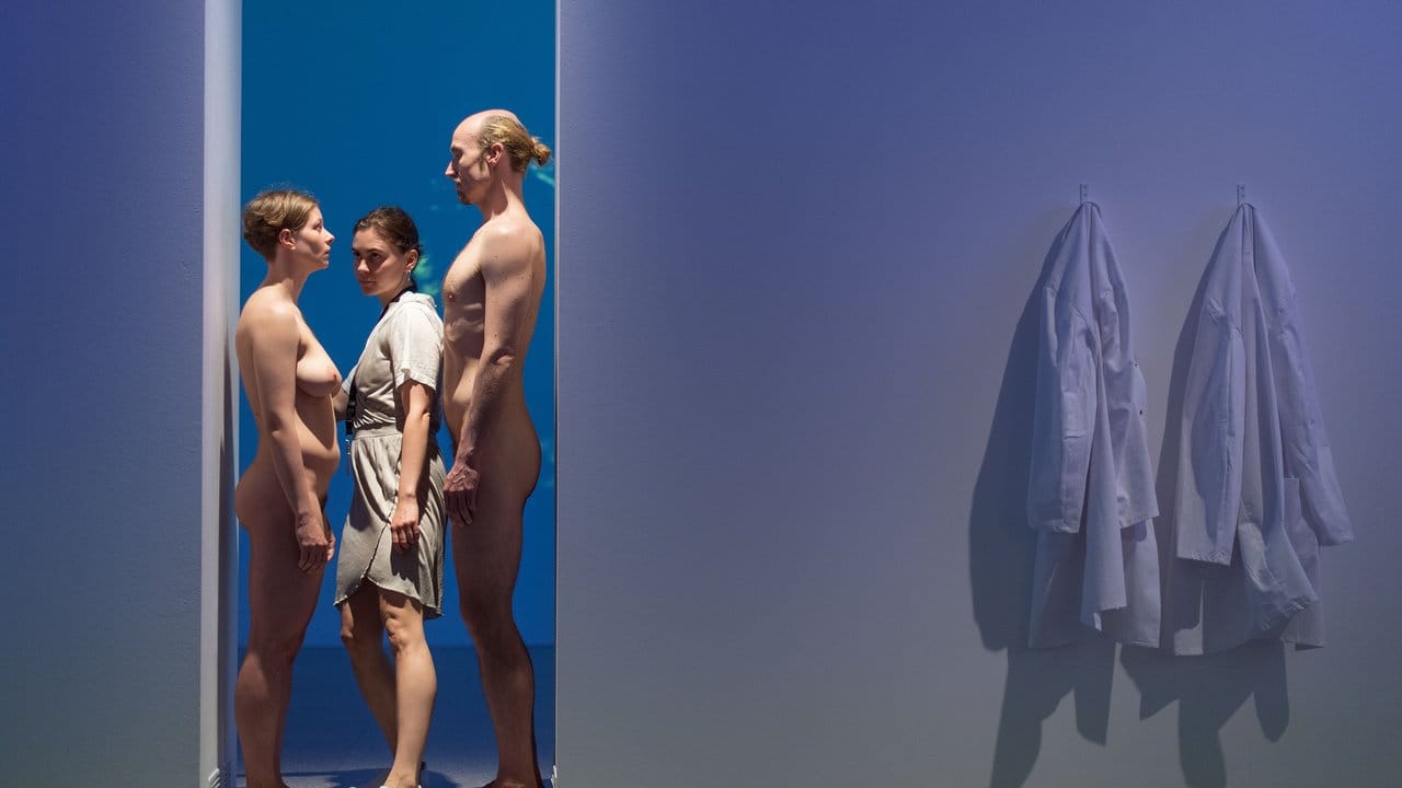 Eine Frau geht in der Bundeskunsthalle zwischen einer nackten Frau und einem nackten Mann hindurch und ist somit Teil einer Re-Perfomance von "Imponderabilia".