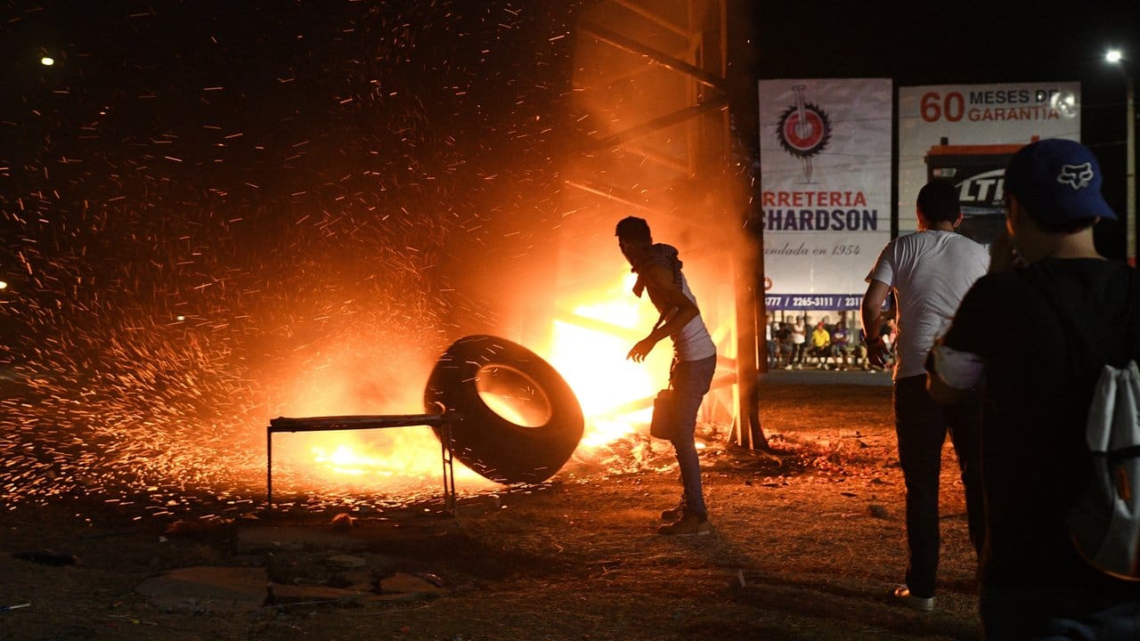 Ein Demonstrant wirft einen Reifen in ein Feuer, das von den Protestlern gelegt wurde.