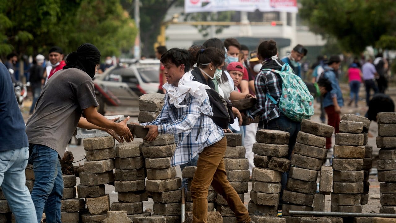 Demonstranten errichten auf einer Straße in Managua eine Barrikade mit Pflastersteinen.
