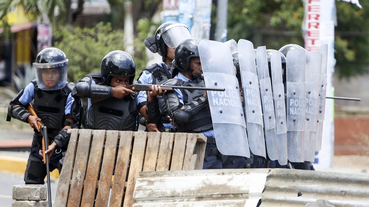 Polizisten zielen in Managua auf Demonstranten.