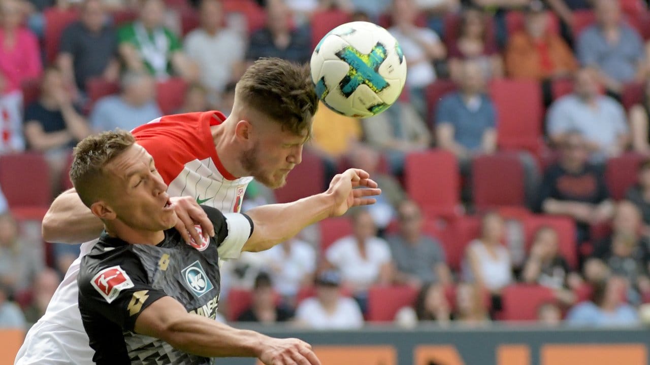Augsburgs Jeffrey Gouweleeuw (hinten) kommt vor dem Mainzer Pablo de Blasis an den Ball.