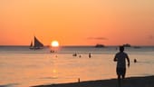 Insel Boracay: Spaziergänger gehen am Strand spazieren und betrachten den Sonnenuntergang.
