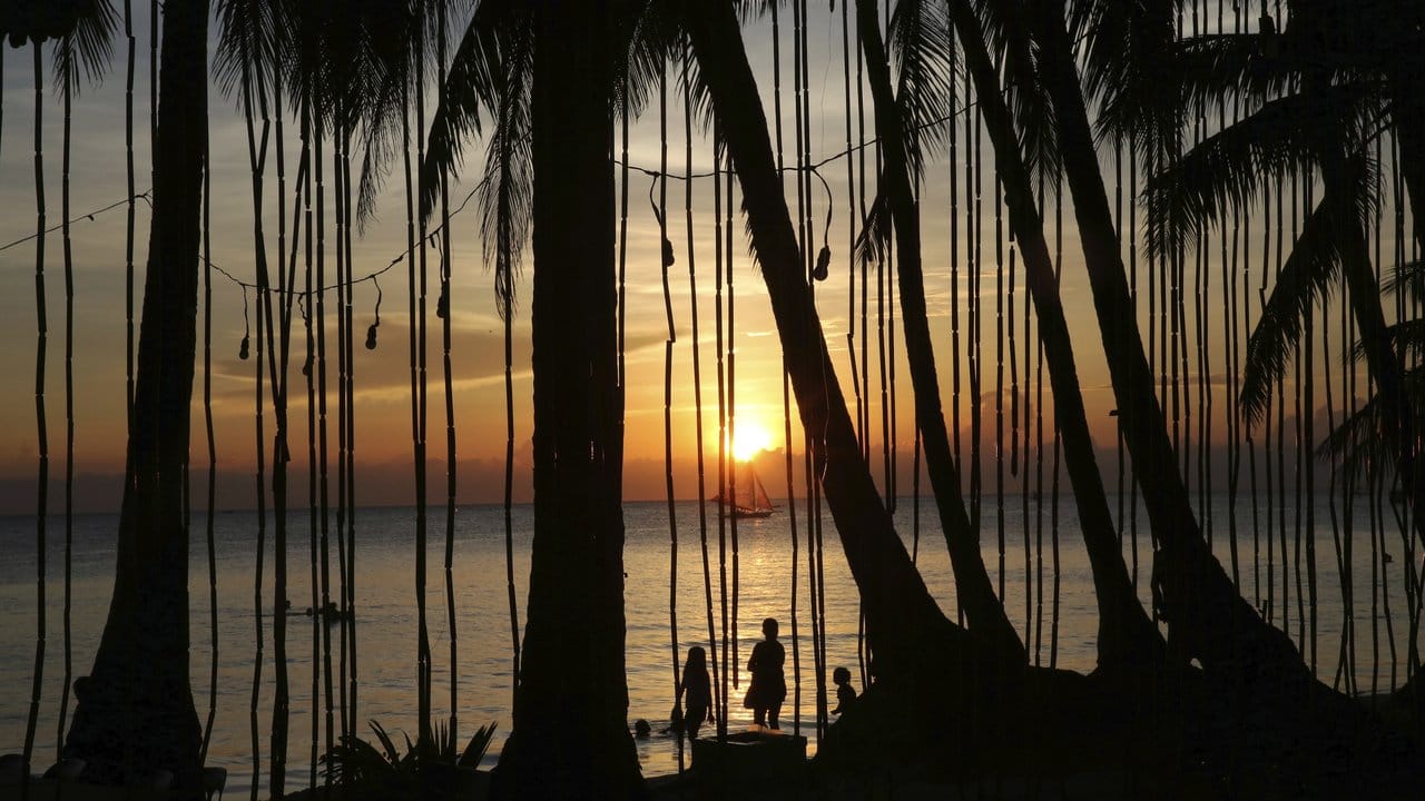 Menschen betrachten den Sonnenuntergang am Strand.