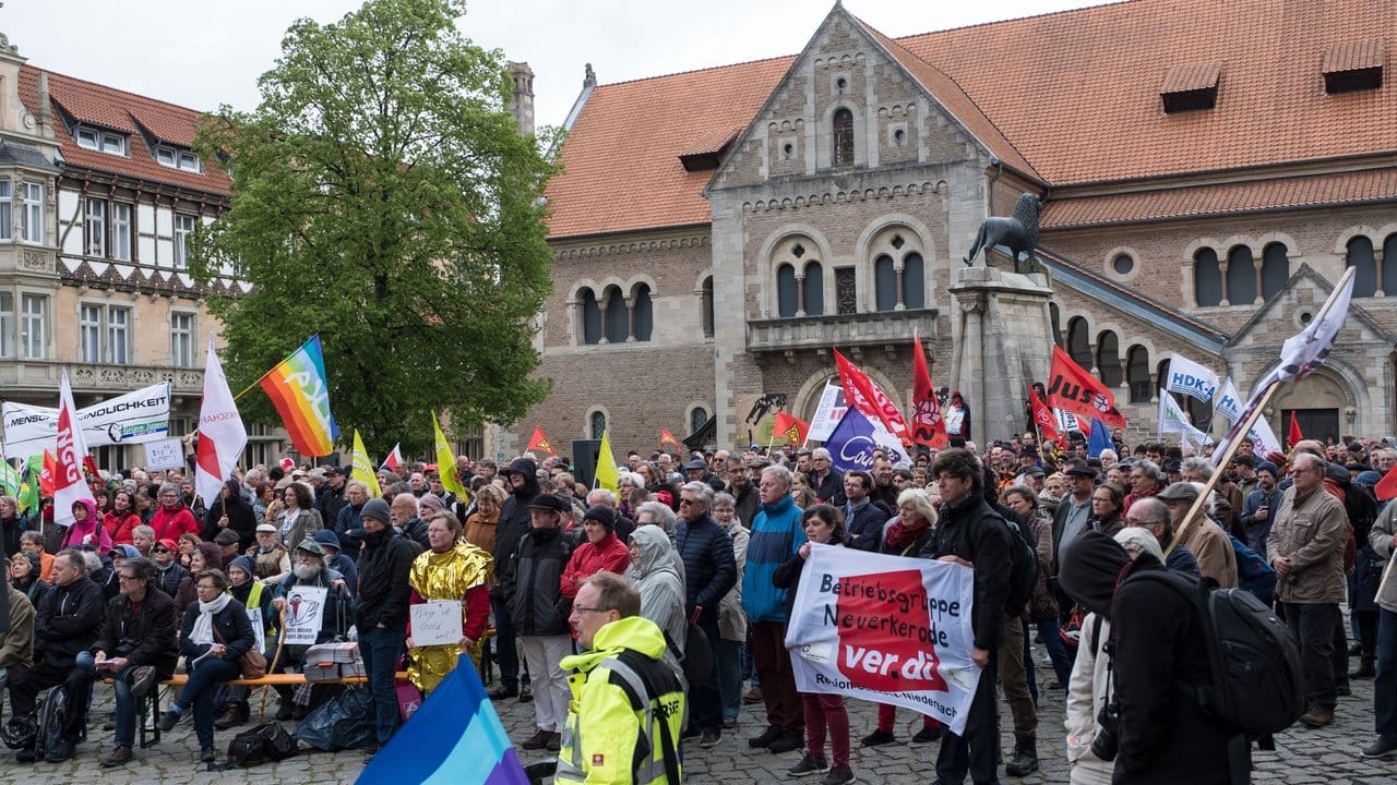 Mit Transparenten und Fahnen nehmen Menschen an der Kundgebung in Braunschweig teil.