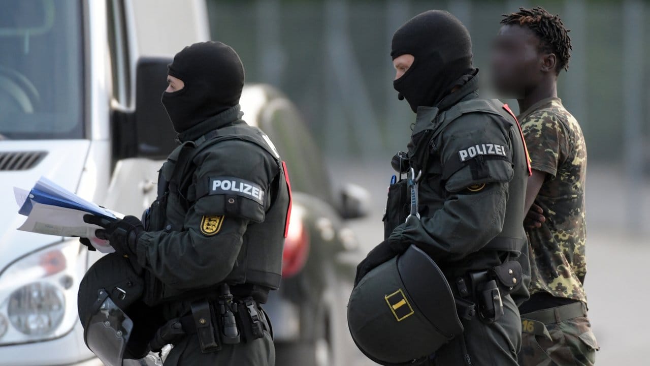 Bei der Großrazzia in der Flüchtlingsunterkunft in Ellwangen wird Flüchtling von Polizisten eskortiert.