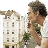 Mann raucht auf dem Balkon