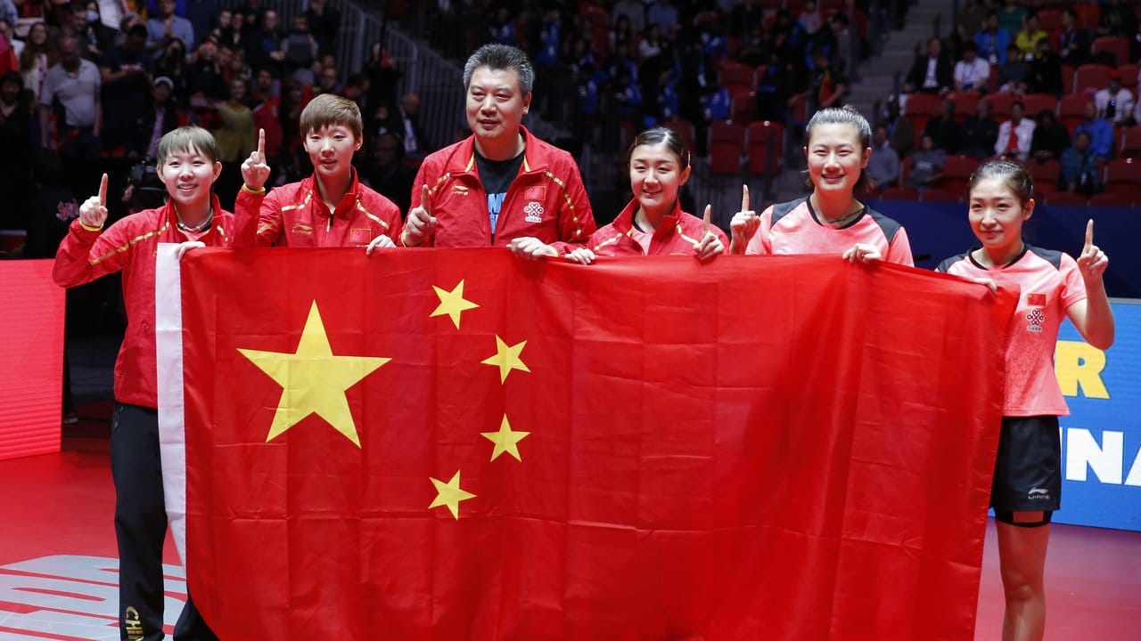 Die Spielerinnen halten zusammen mit Trainer Li Sun (3.