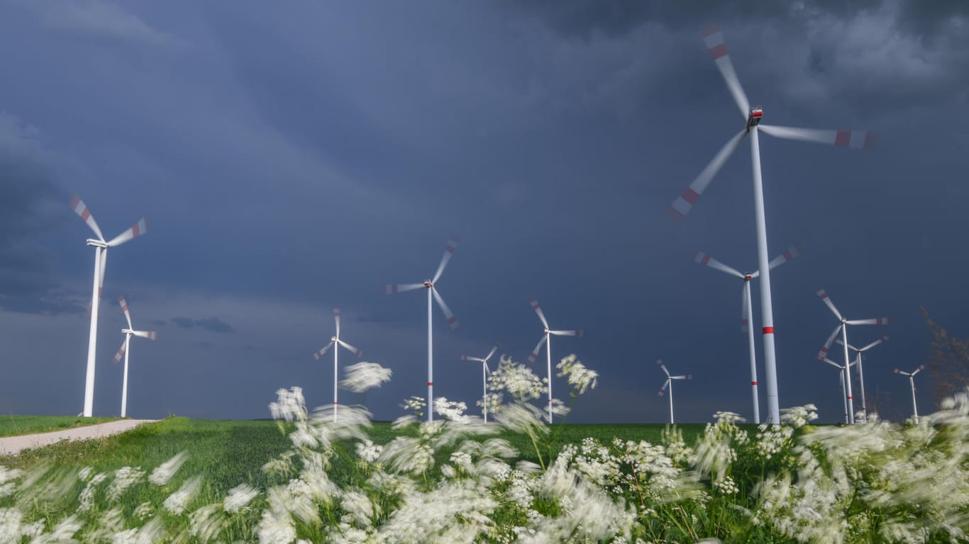 Gewitterwolken ziehen über ein Feld mit Windenergieanlagen in Brandenburg: Ab Dienstag werden im Osten und in der Mitte Deutschlands Gewitter erwartet.