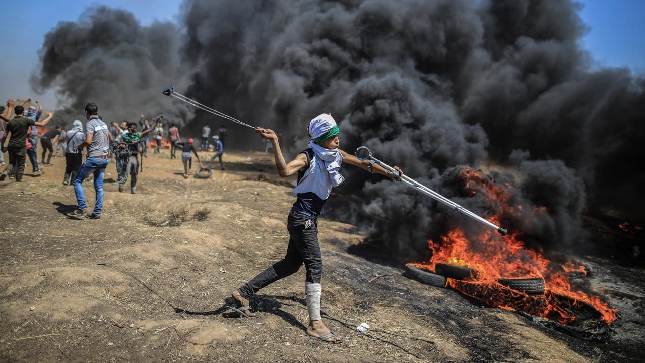 Ein Palästinenser schleudert Steine auf israelische Soldaten.
