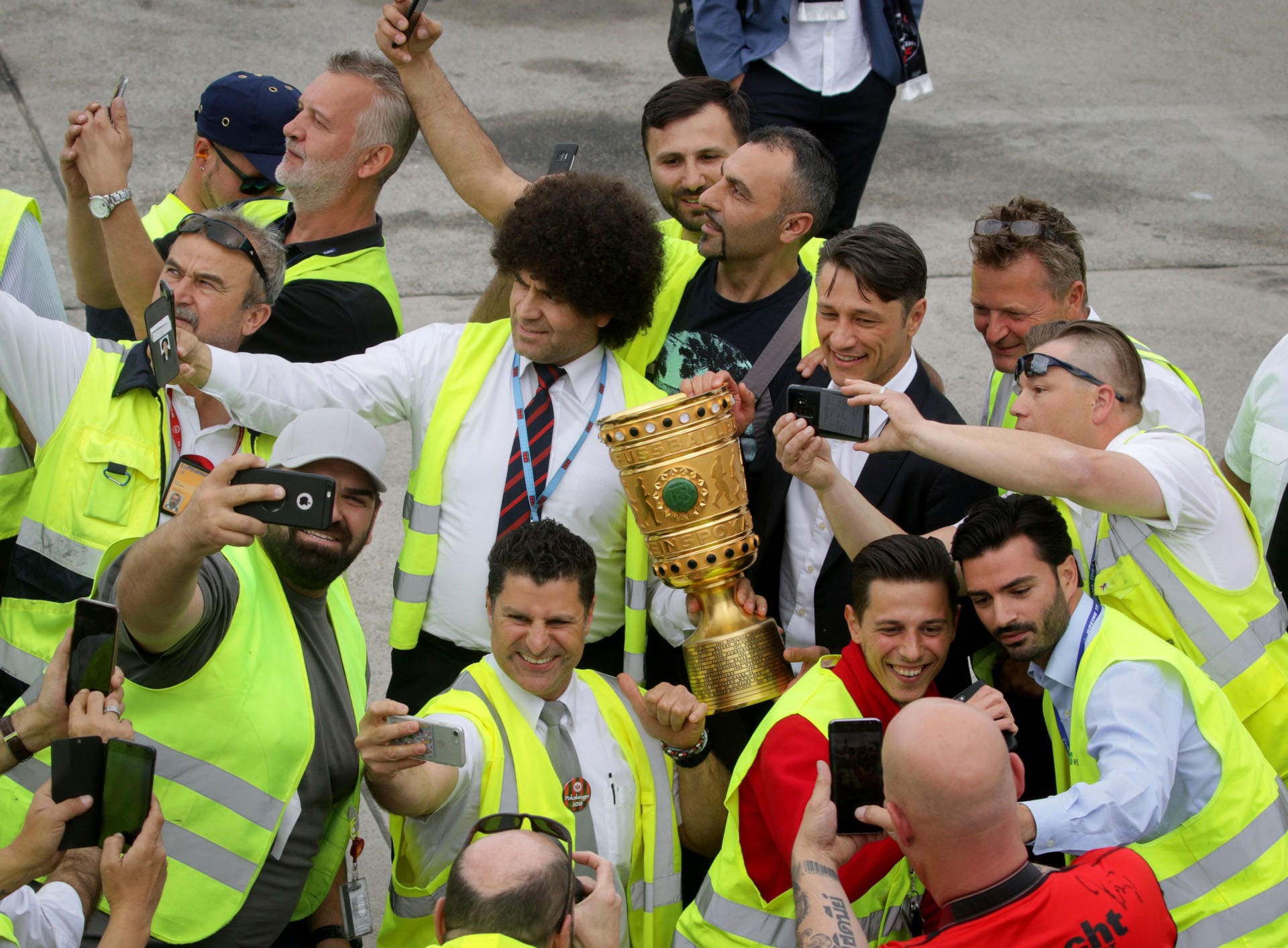 Flughafen-Bedienstete und Trainer Niko Kovac (r) machen nach der Landung auf dem Frankfurter Flughafen Fotos mit dem DFB -Pokal.