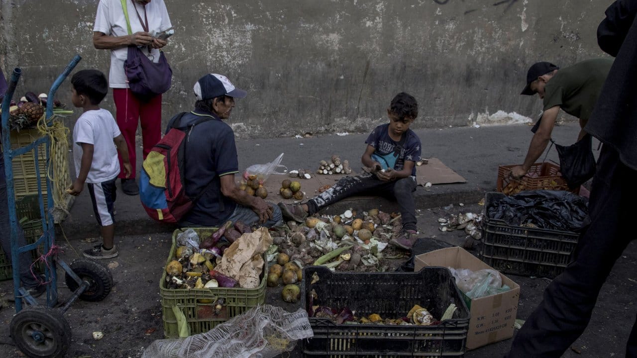 Die Wirklichkeit in Venezuela: Menschen sammeln in der Nähe eines Straßenmarkts Gemüse- und Obstreste auf. Die Wirklichkeit in Venezuela: Menschen sammeln in der Nähe eines Straßenmarkts Gemüse- und Obstreste auf.