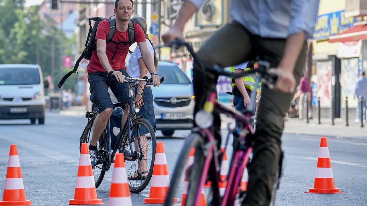 Aktivisten fahren auf der Karl-Marx-Straße in Berlin mit ihren Fahrrädern auf einem Radweg, durch Warnkegelen markiert ist. Aktivisten fahren auf der Karl-Marx-Straße in Berlin mit ihren Fahrrädern auf einem Radweg, durch Warnkegelen markiert ist.