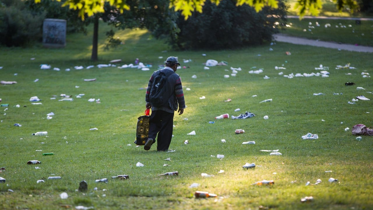 Ein Flaschensammler geht am frühen Morgen über eine mit Abfällen übersäte Wiese im Herrngarten am Rande der Innenstadt. Ein Flaschensammler geht am frühen Morgen über eine mit Abfällen übersäte Wiese im Herrngarten am Rande der Innenstadt.