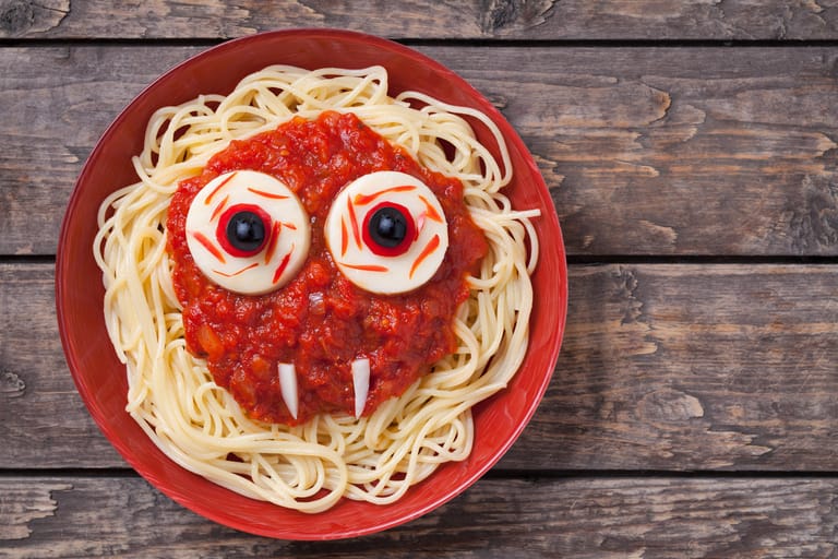 Vampir-Monstergesicht mit großen Augen: Sie können Spaghetti mit Tomatensoße mit zwei runden Käse- oder Apfelscheiben dekorieren, in deren Mitte Sie Oliven oder schwarze Johannisbeeren als Augen setzen. Zwei Radieschenstifte wirken als scharfe Eckzähne.