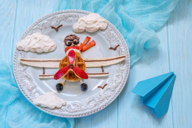 So fängt der Tag richtig gut an: Lustiges Flugzeugfrühstück für Kinder – mit Apfel, Banane, Erdbeere, Heidelbeeren und Schokolade.