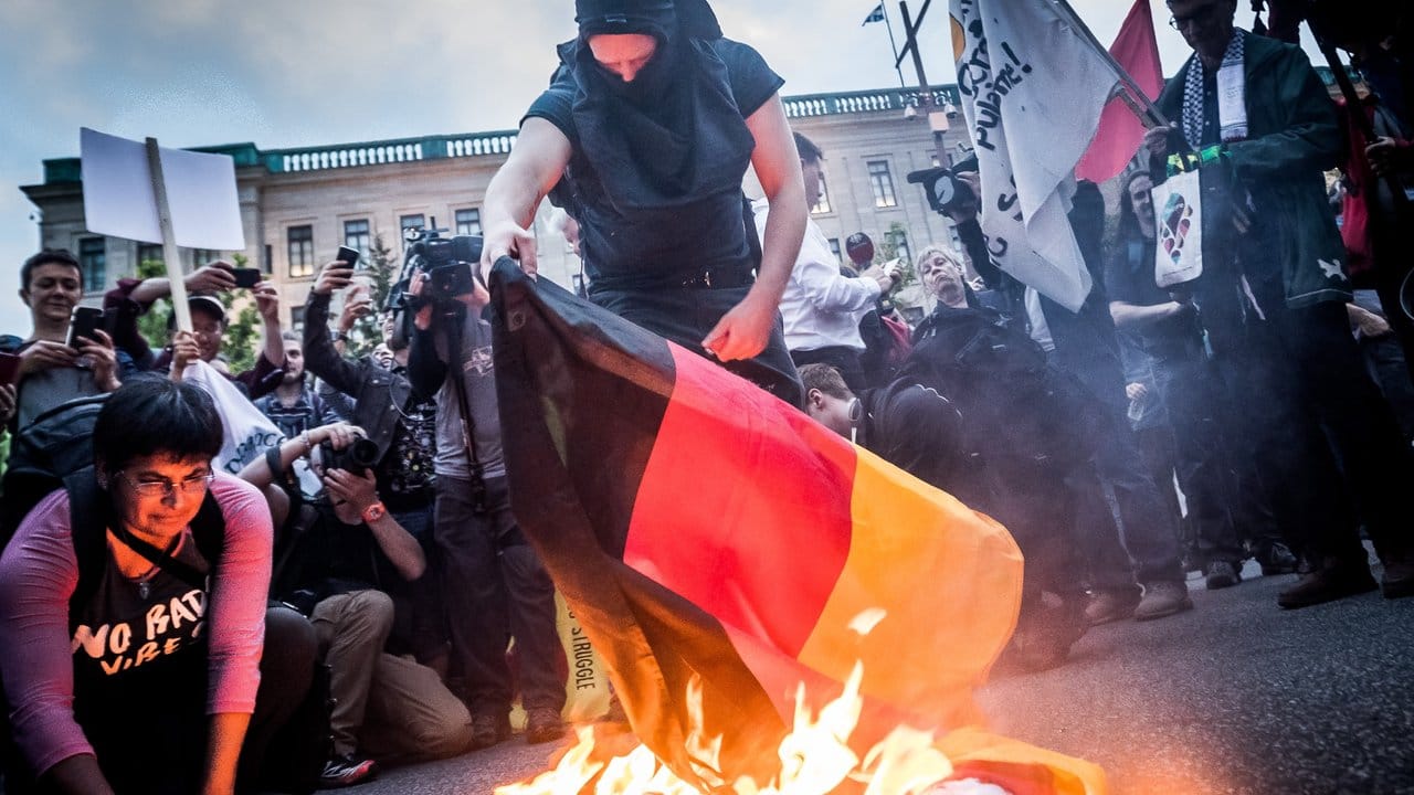 Demonstranten verbrennen in Quebec eine deutsche Flagge.
