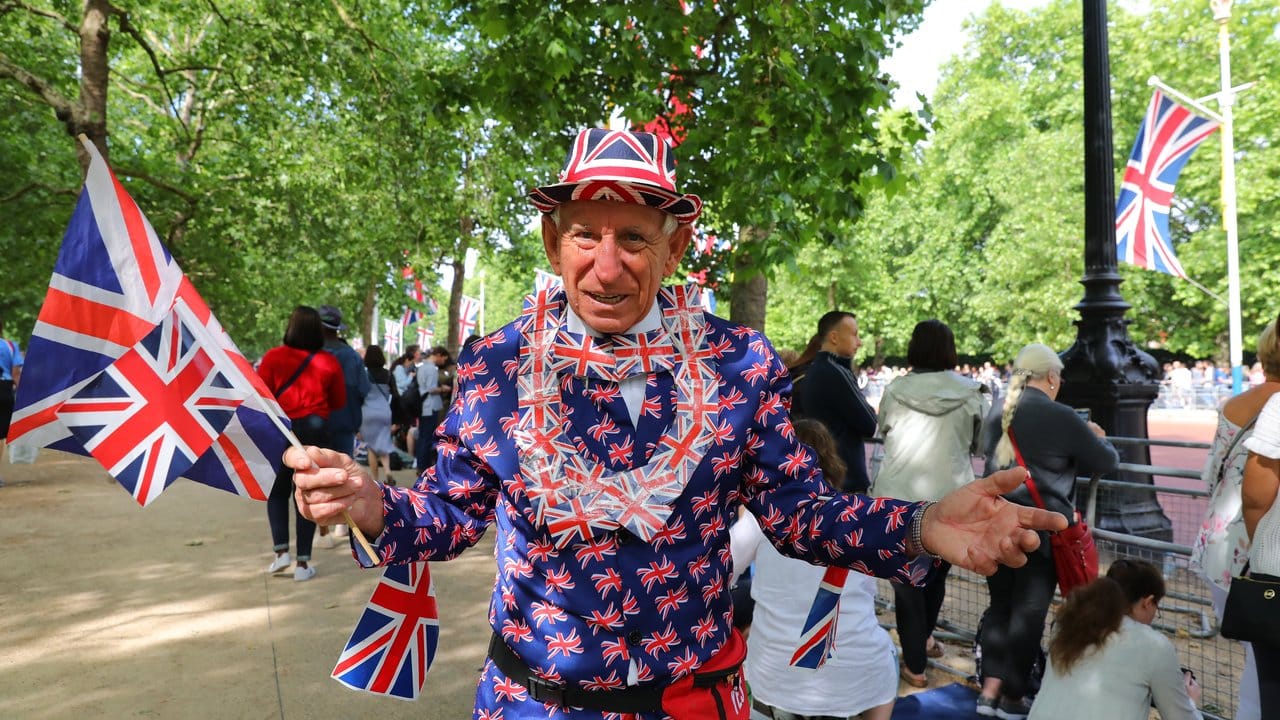 Im Kostüm aus Flaggen des Vereinigten Königreichs wartet ein Zuschauer auf die Militärparade.