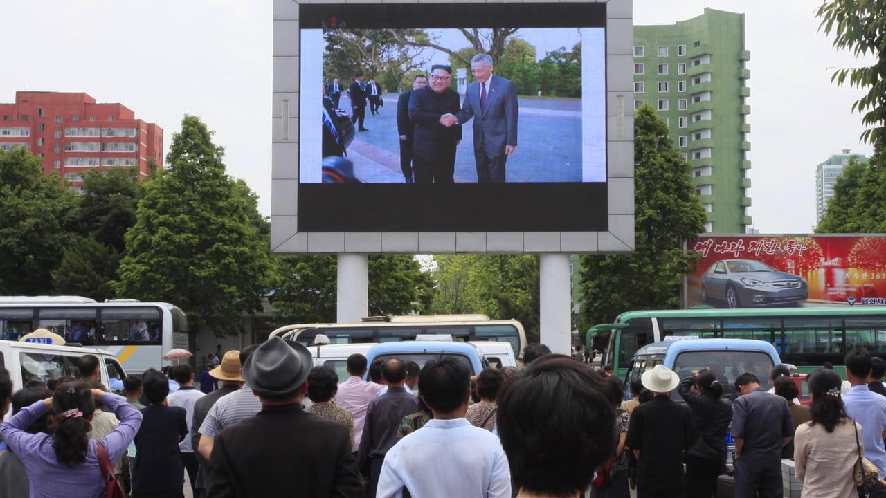 Am Hauptbahnhof von Pjöngjang verfolgen Passanten ein Video mit Nordkoreas Machthaber bei seiner Ankunft in Singapur.
