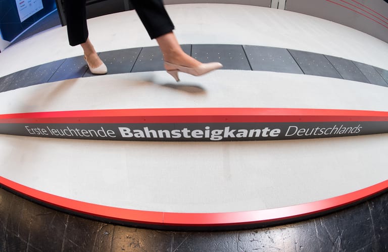 Eine Frau läuft bei der Digitalisierungsmesse Cebit am Stand der Deutschen Bahn über die erste leuchtende Bahnsteigkante Deutschlands. Die Bahnsteigkante zeigt bei der Einfahrt des Zuges, wo sich die Türen befinden und Sitzplätze frei sind.
