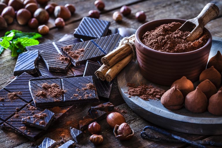 Dunkle Schokolade und Pulver auf einem dunklen Holztisch ausgebreitet