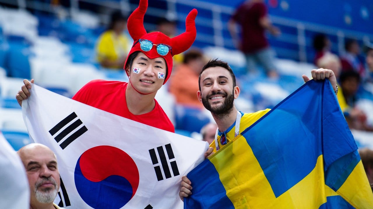 Fans aus Südkorea (l) und Schweden feiern gemeinsam den WM-Start ihrer Teams auf der Tribüne.