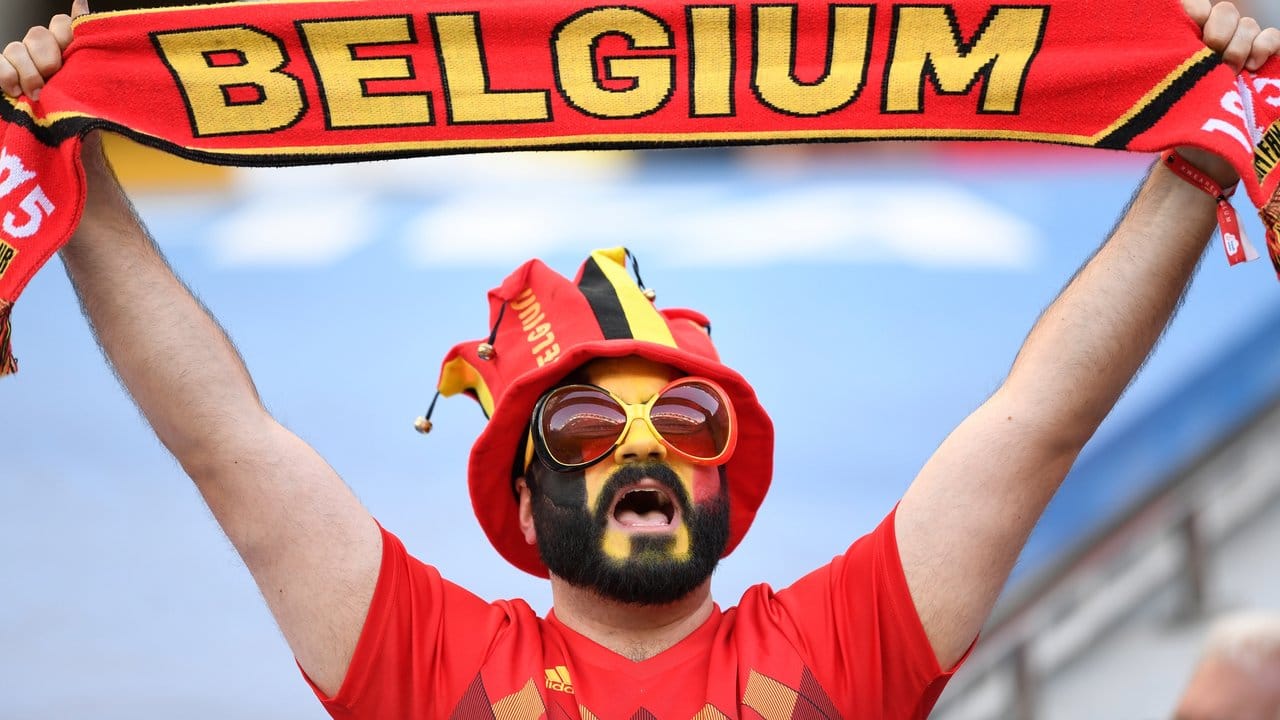 Ein im Gesicht geschminkter Belgien-Fan hält einen Schal hoch.