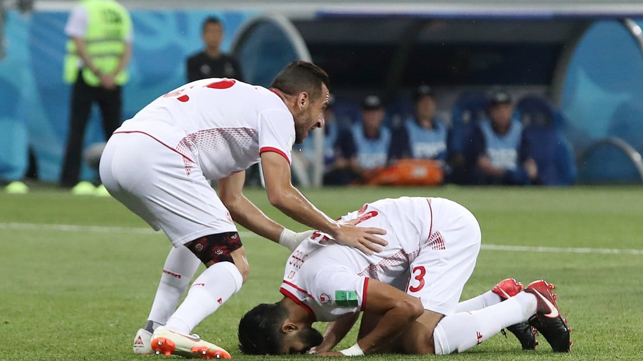 Der Tunesier Ferjani Sassi (r) küsst nach seinem getroffenen Elfmeter zum 1:1 neben Ali Maaloul den Rasen.