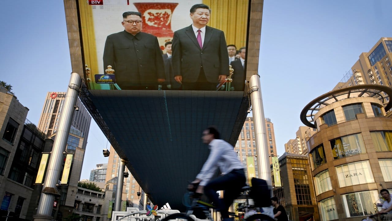 Auf einem riesigen Bildschirm in Peking wird die Begrüßung von Kim Jong Un und Xi Jinping übertragen.