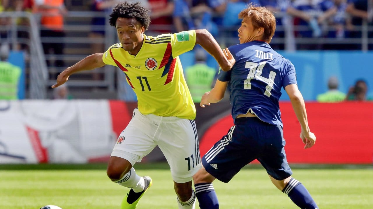 Kolumbiens Juan Cuadrado (l) spitzelt den Ball an Japans Takashi Inui vorbei.