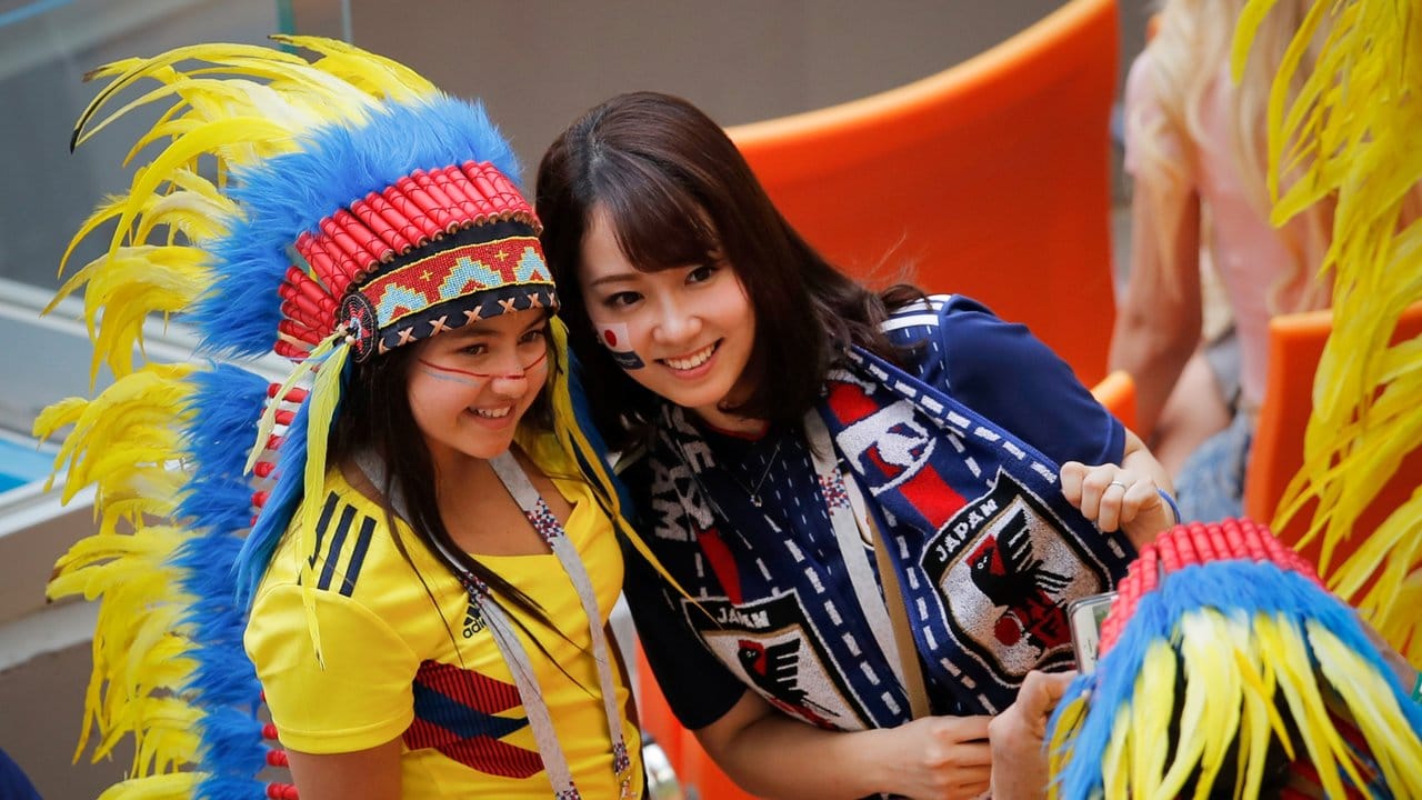 Weibliche Fans aus Kolumbien (l) und Japan posieren für gemeinsame Fotos im Stadion.