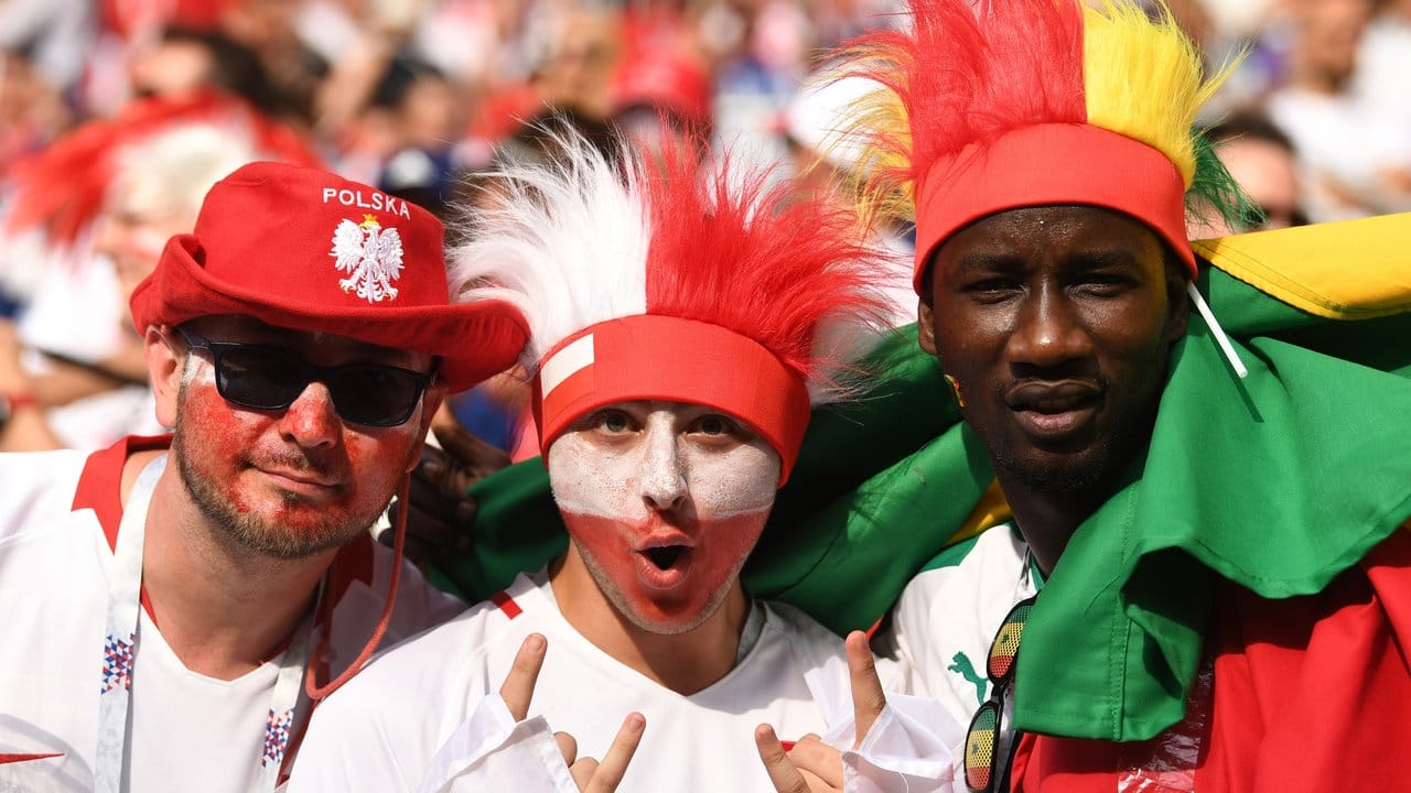 Fans aus Polen und dem Senegal feiern gemeinsam den Turnierauftakt ihrer Mannschaften auf der Tribüne.