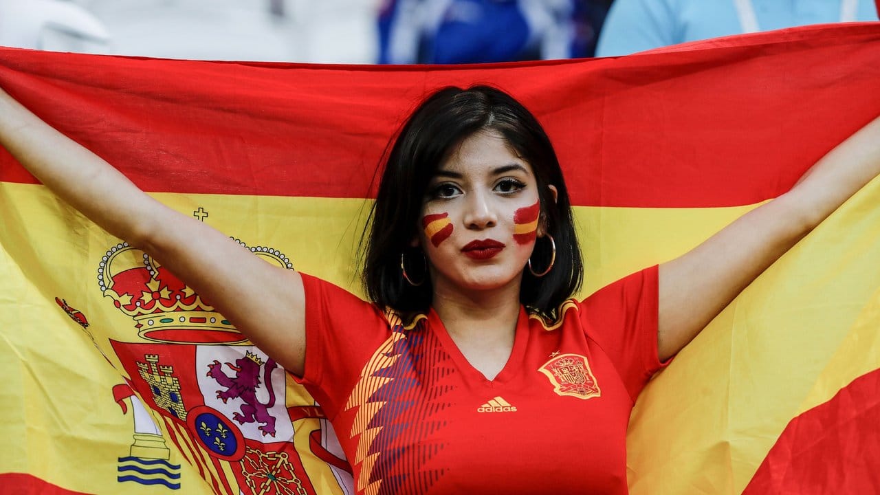 Ein weiblicher spanischer Fan steht vor Spielbeginn mit einer spanischen Flagge im Stadion.