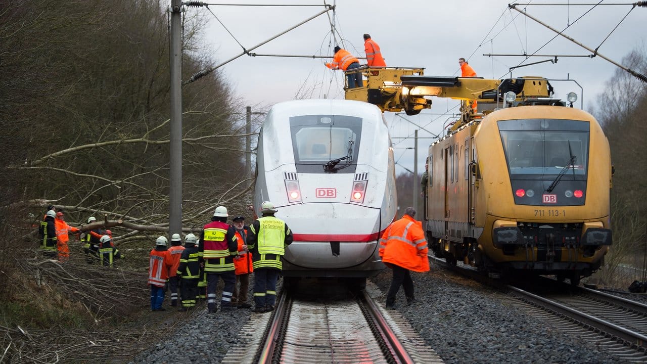 Neben einem liegengebliebenen ICE arbeiten Techniker der Bahn an einer durch den Sturm beschädigten Oberleitung. Neben einem liegengebliebenen ICE arbeiten Techniker der Bahn an einer durch den Sturm beschädigten Oberleitung.