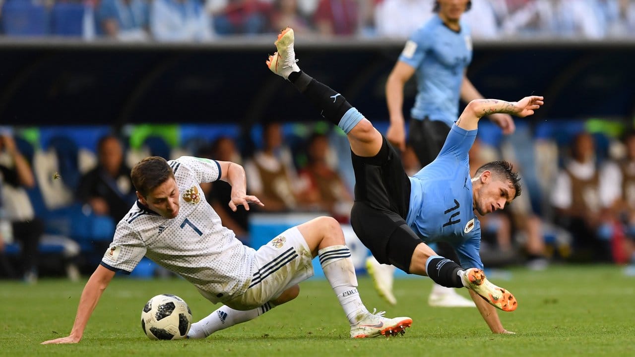 Russlands Daler Kusjajew (l) und Uruguays Lucas Torreira kämpfen mit vollem Körpereinsatz um den Ball.