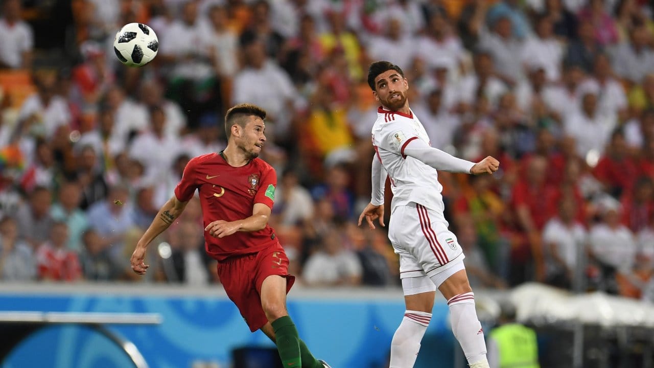 Der Iraner Alireza Jahanbakhsh (r) gewinnt das Kopfballduell gegen Portugals Raphael Guerreiro.