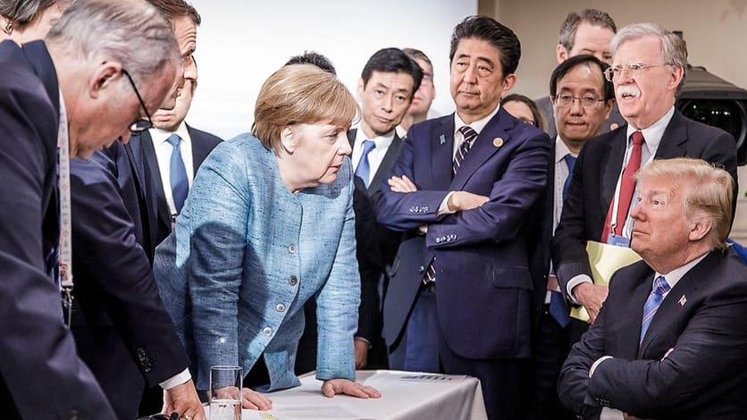 Merkel beim G7-Treffen in Kanada mit einem Donald Trump, der ihre Welt mit verschränkten Armen auflaufen lässt.