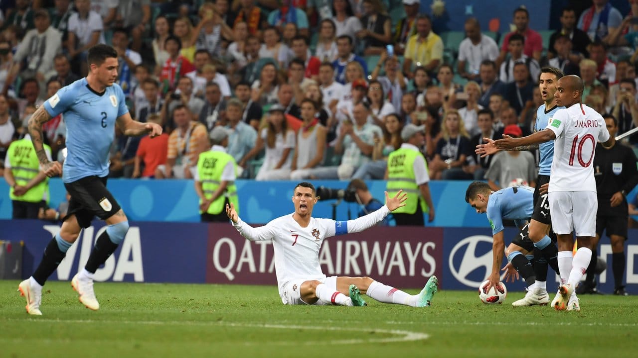 Cristiano Ronaldo (M) sitzt auf dem Platz und beschwert sich.