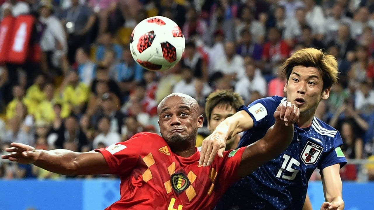 Belgiens Vincent Kompany (l) räumt beim Kampf um den Ball den Japaner Yuya Osako beiseite.