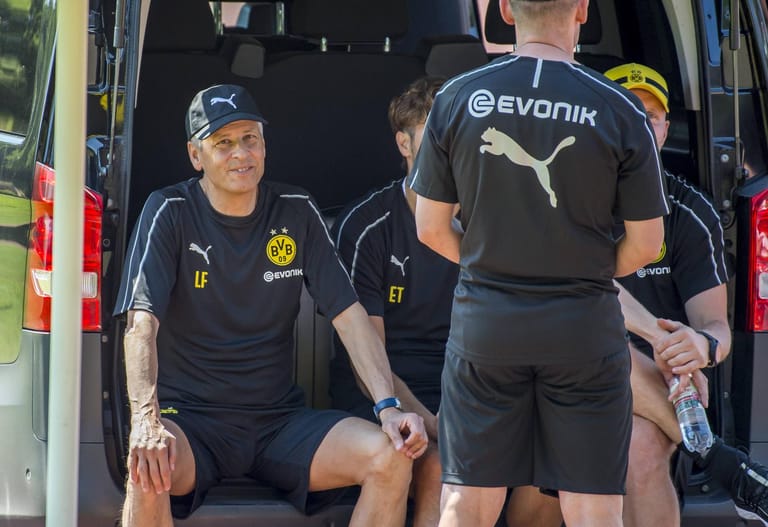 Dortmunds neuer Trainer Lucien Favre beobachtet gut gelaunt aus dem Kofferraum eines Autos den Lauftest der BVB-Spieler.