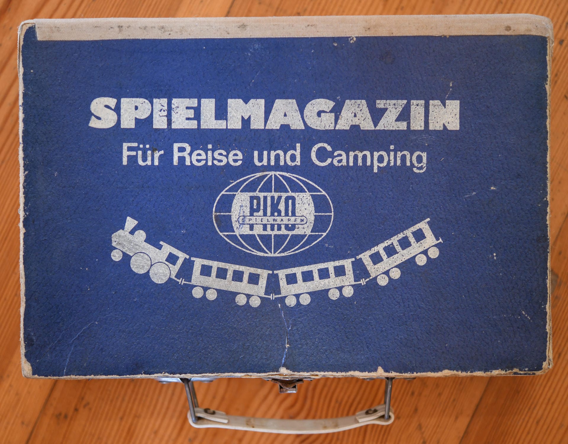 Ein kleiner Koffer mit der Aufschrift "Spielemagazin für Reise und Camping PIKO Spielwaren" aus DDR-Zeiten ist in der Ausstellung zu sehen.