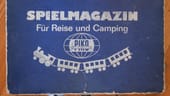 Ein kleiner Koffer mit der Aufschrift "Spielemagazin für Reise und Camping PIKO Spielwaren" aus DDR-Zeiten ist in der Ausstellung zu sehen.